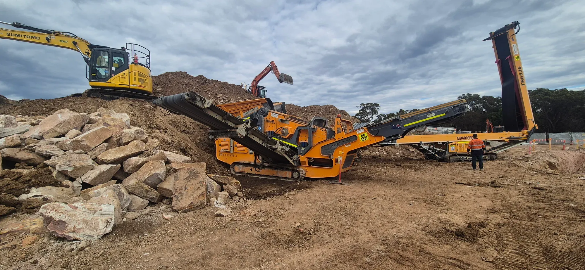 Mobile jaw crusher and tracked stacker working a civil site